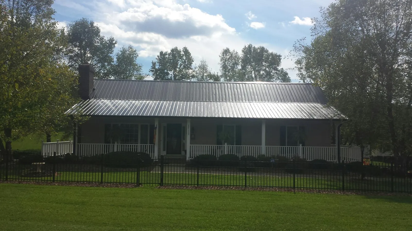 Gray metal roof on a brick ranch with a full width front porch — Gutter Guard Installation work by our crew in Harris